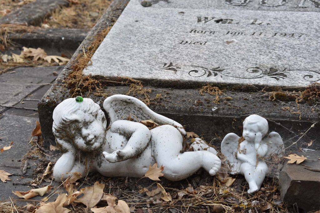 Two angel figurines beside a grave