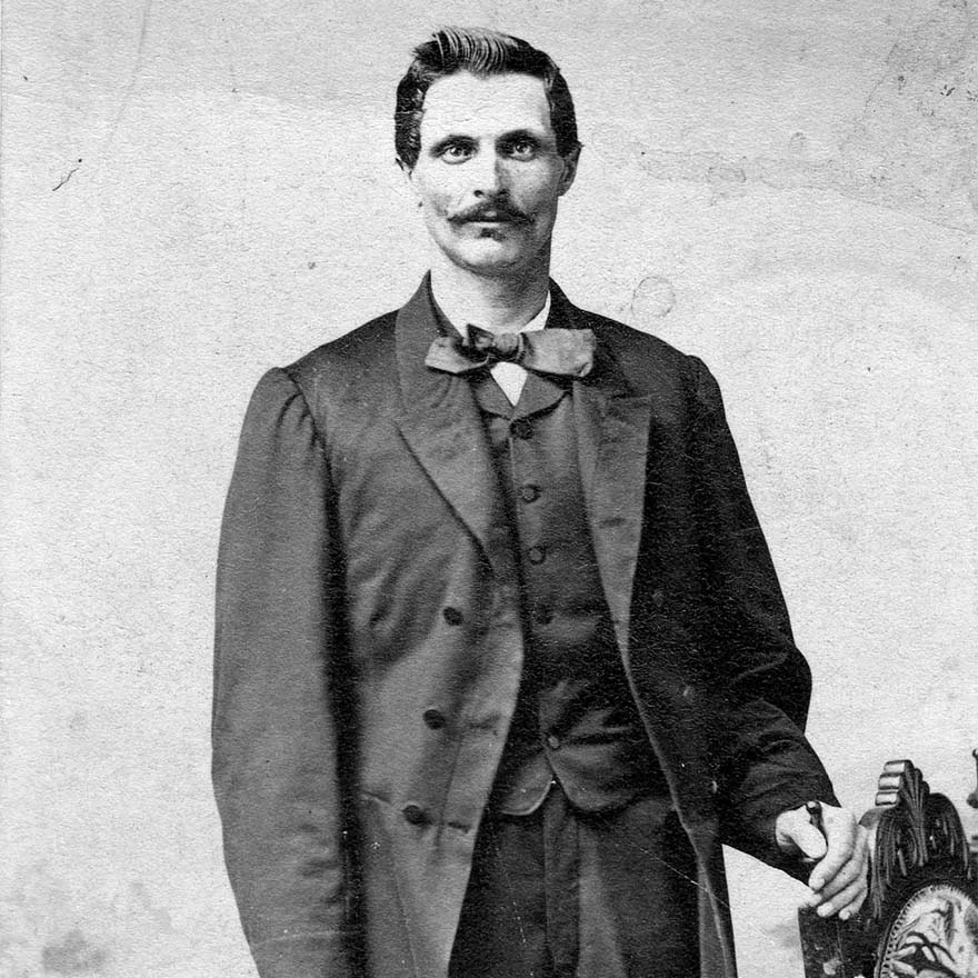 A black and white photo of a man with a mustache wearing a suit
