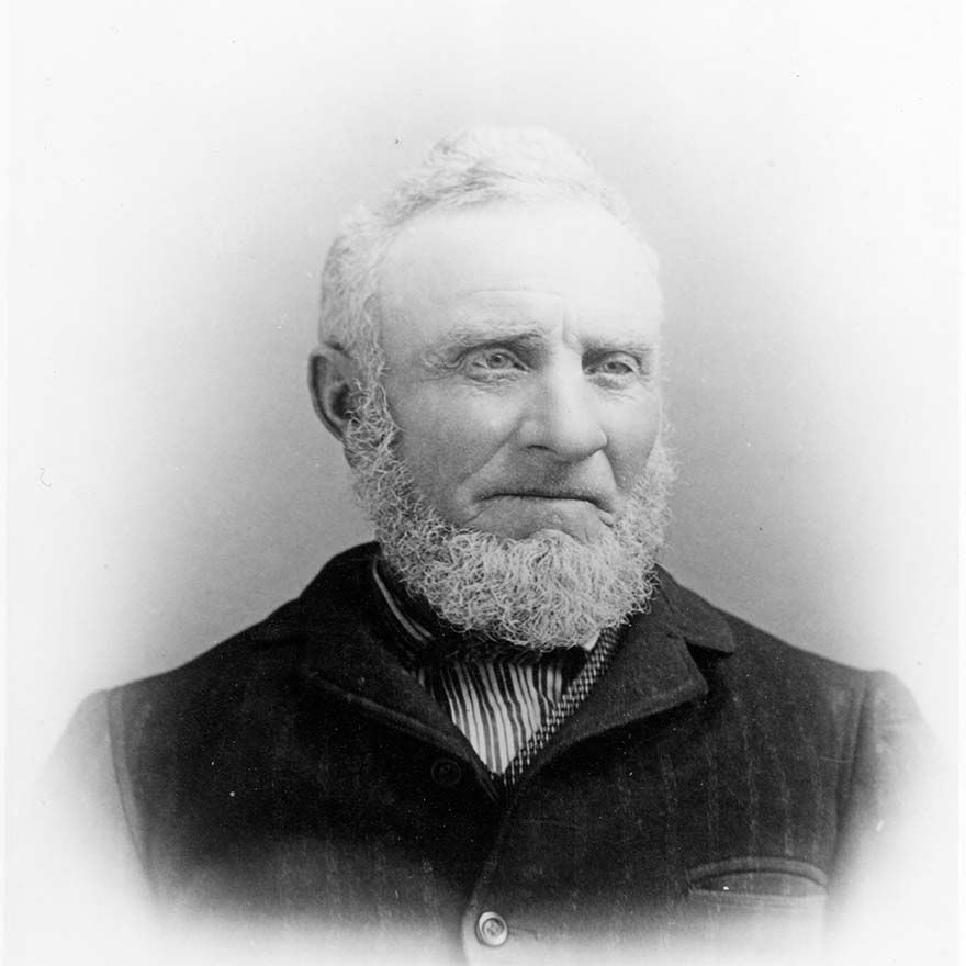 A black and white photo of a man with a white beard and a serious face